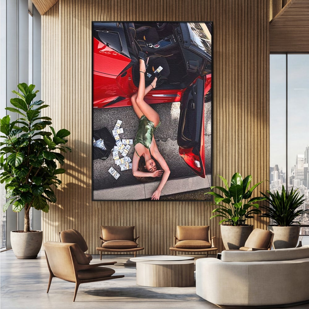 Tablou canvas cu femeie intinsa langa masina rosie si bancnote, in rama de aluminiu negru, pe perete intr-un birou